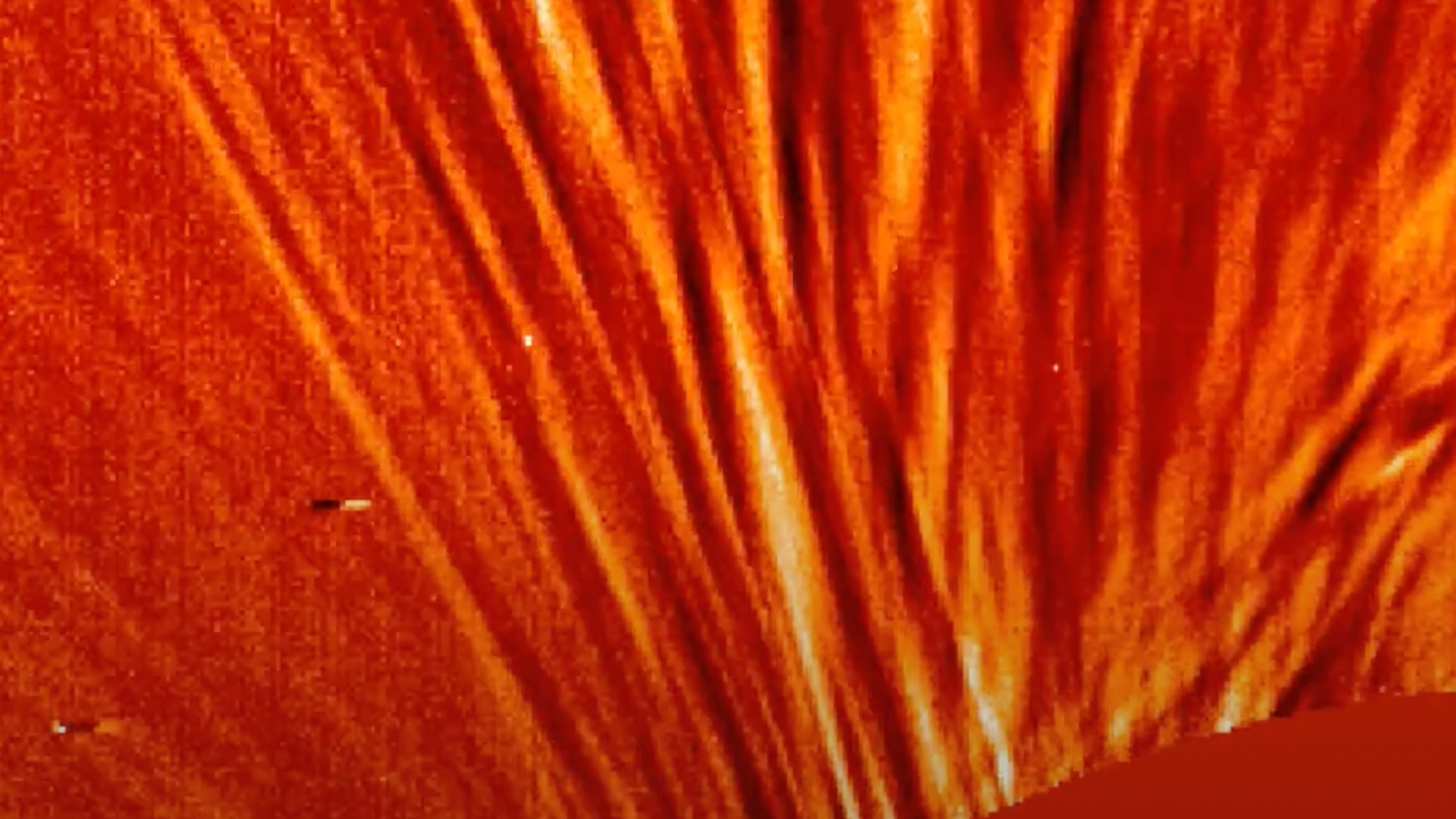 spacecraft view of a solar eruption, showing streamers of orange and yellow plasma coming from the sun