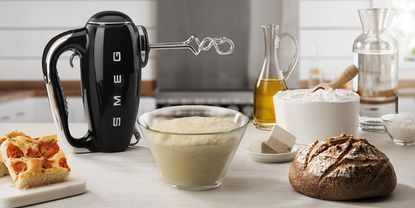 Image of one of the best stand mixers, Smeg Retro 1950s hand mixer in lifestyle image being used to make bread 