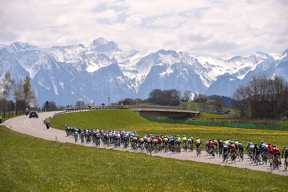 Mountains rise in the background as the peloton makes its way to the finish of stage 4 at the Tour de Romandie.