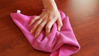 Wiping down wood table with pink cloth