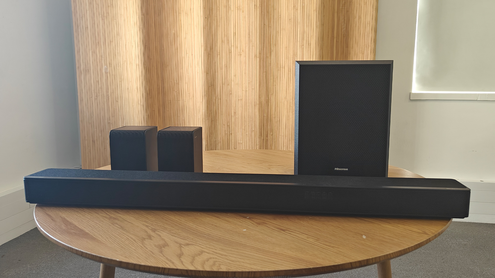 The Hisense AX5125H Dolby Atmos soundbar system, pictured on a round, wooden table