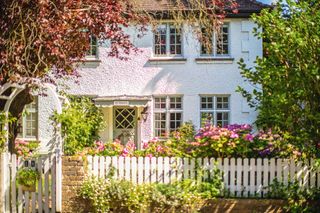 front of edwardian home with white picket fence and rose arch