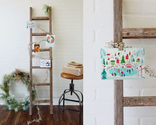 A wooden ladder with garland and Christmas cards used as a display feature
