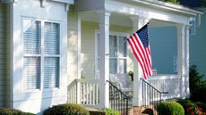 A US flag on a flagpole on a porch 