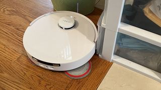 Yeedi M12 Ultra Plus robot vacuum with mop pad extended, near the corner of a room