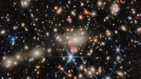 An image of deep space, where blue, red and orange stars twinkle next to golden and orange galaxies.