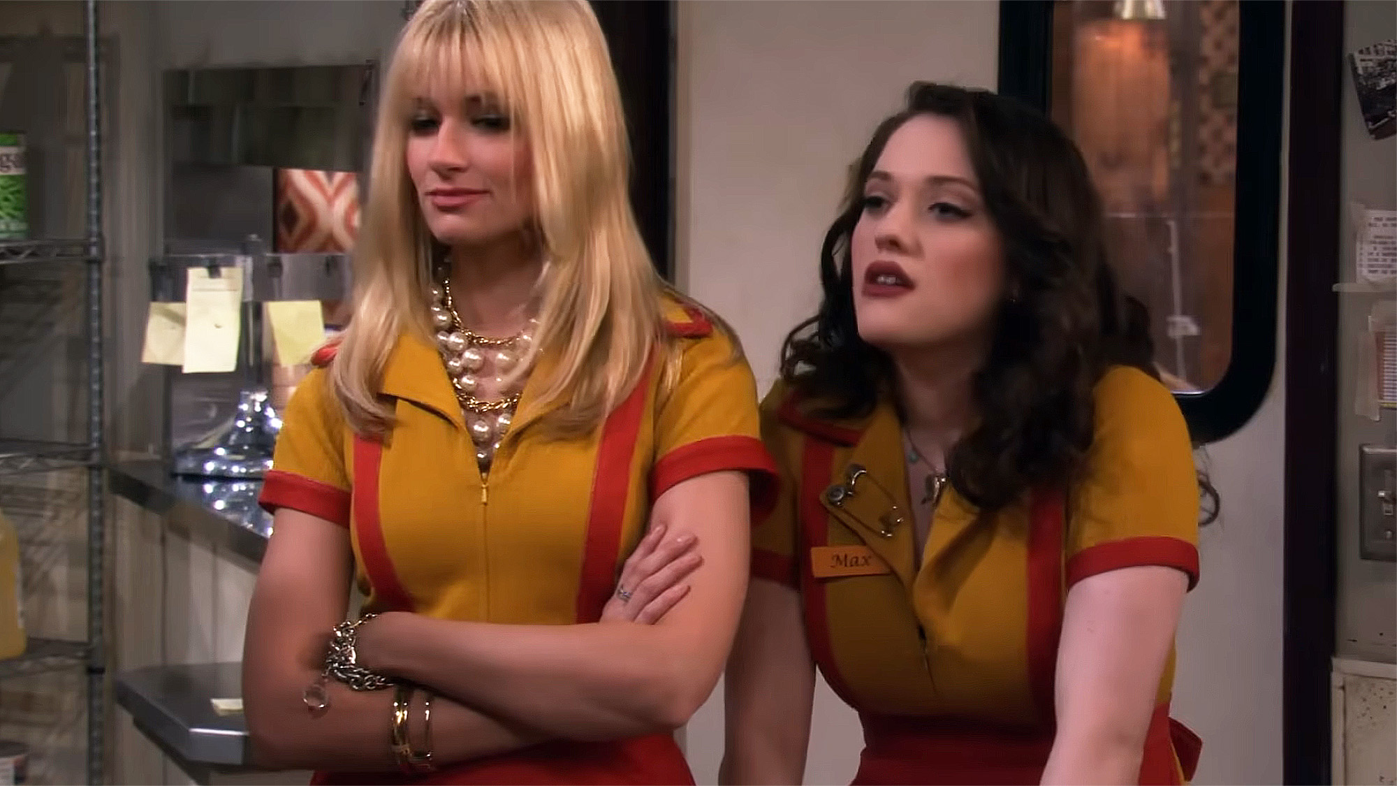 Beth Behrs as Caroline and Kat Dennings as Max both in their yellow and red uniforms on 2 Broke Girls.