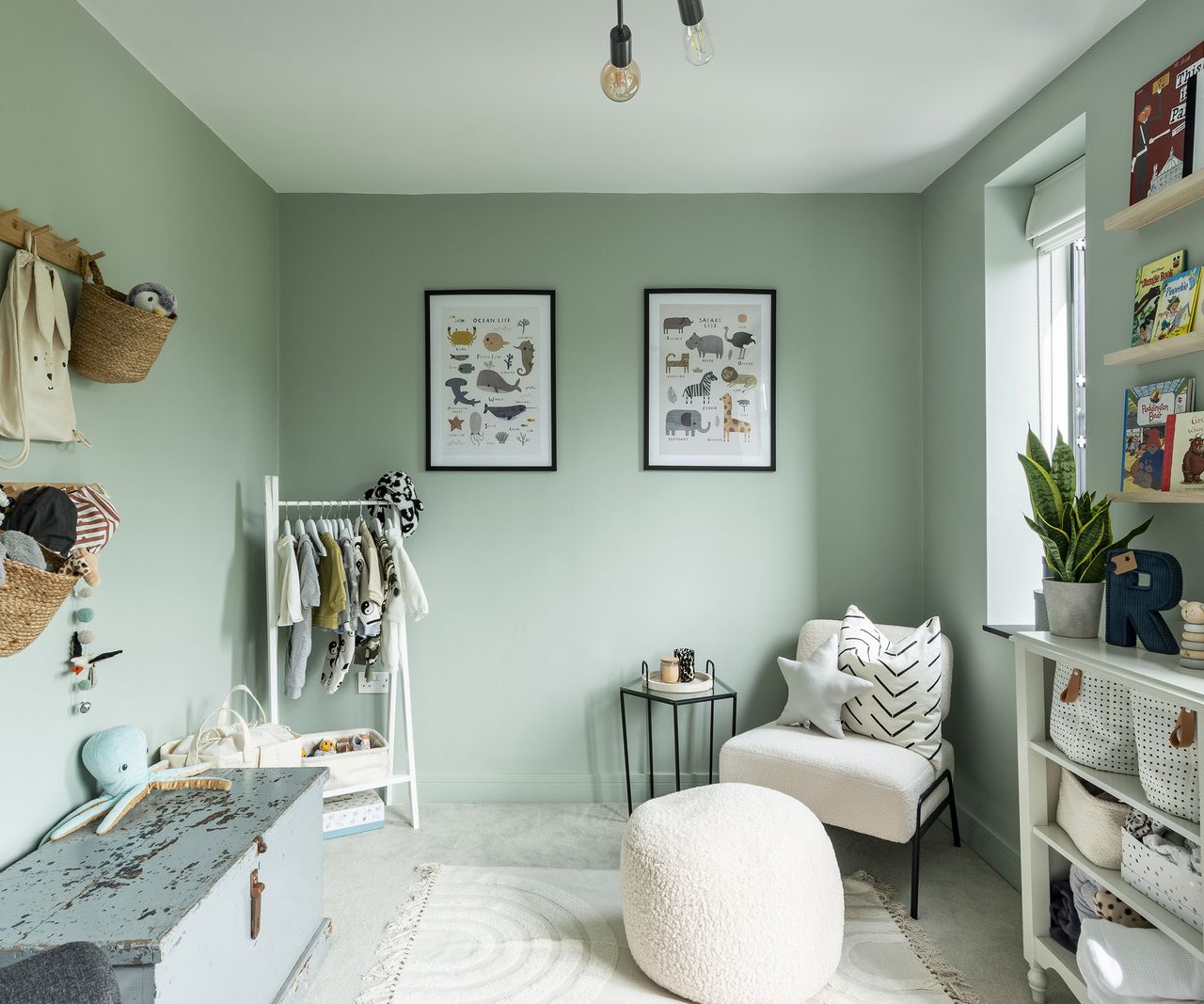 A mint green child's bedroom styled with pale furniture and personal touches such as animal wall prints and book cases