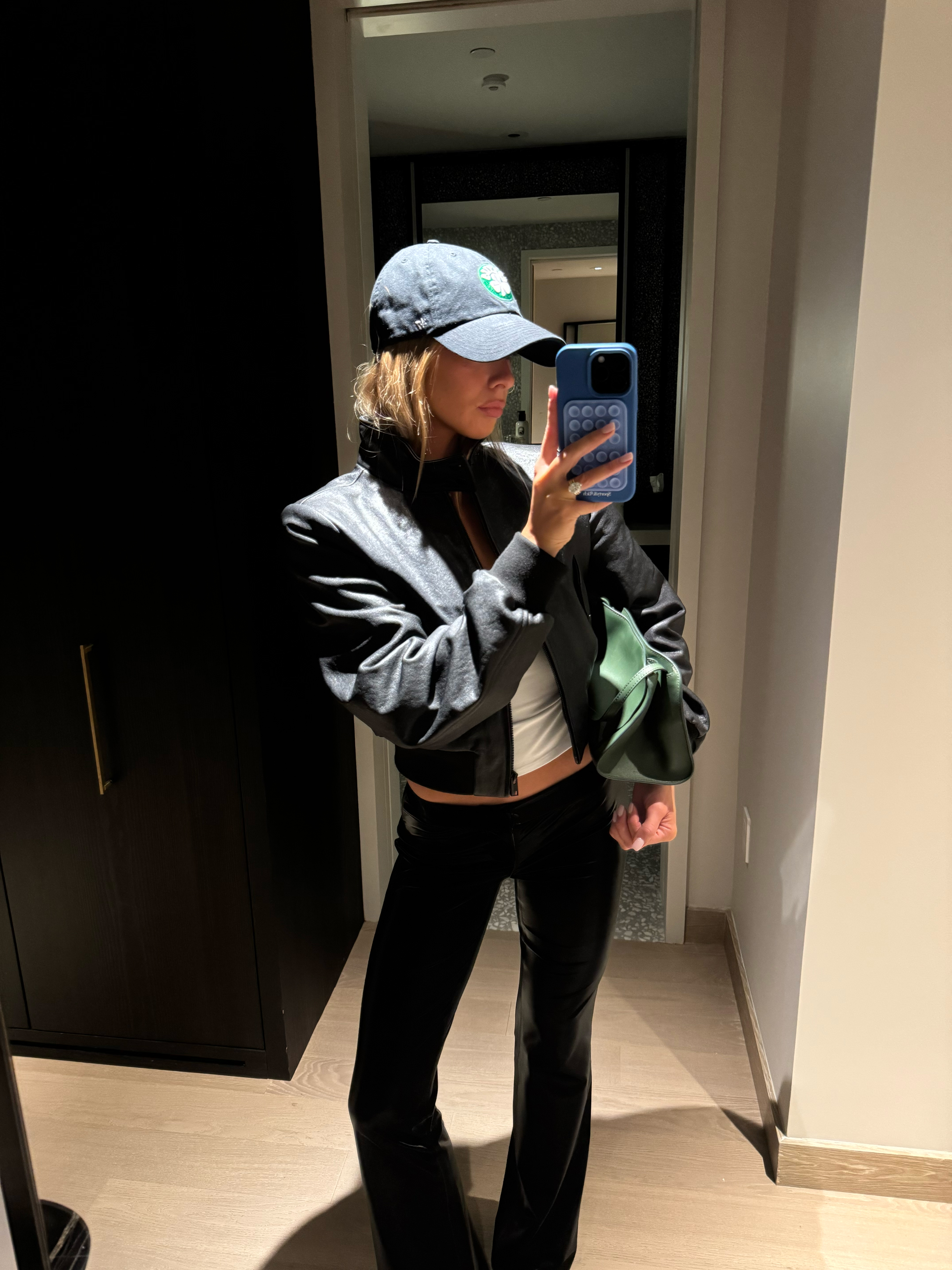 Emma Pritchard wearing a baseball cap, bomber jacket, and black trousers.