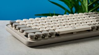 A photo of the Logitech Pop Keys keyboard on a stone surface against a blue background