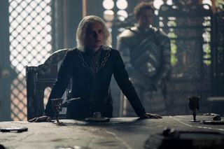 Tom Glynn-Carney dans le rôle d'Aegon Targaryen, debout à la table du Petit Conseil, dans « La Maison du Dragon »