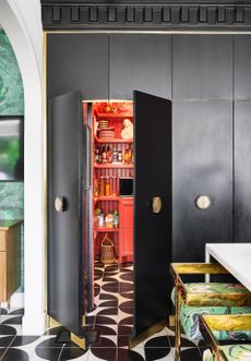 colourful kitchen with patterns, black and white floor, black cabinetry and red walk in pantry