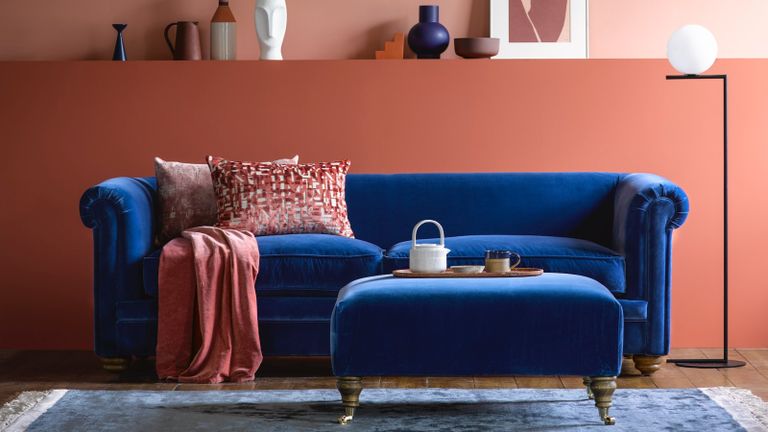 A navy blue velvet Chesterfield sofa in a terracotta-painted living room 