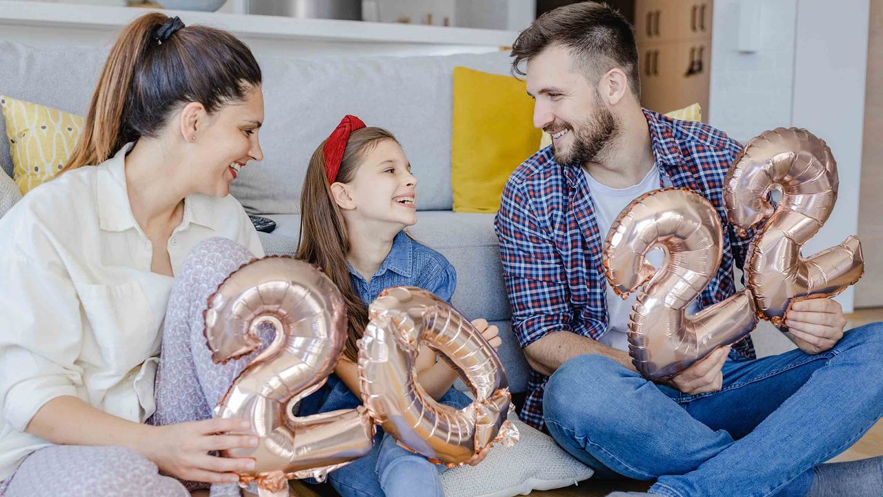 picture of family in their living room holding 2022 balloons