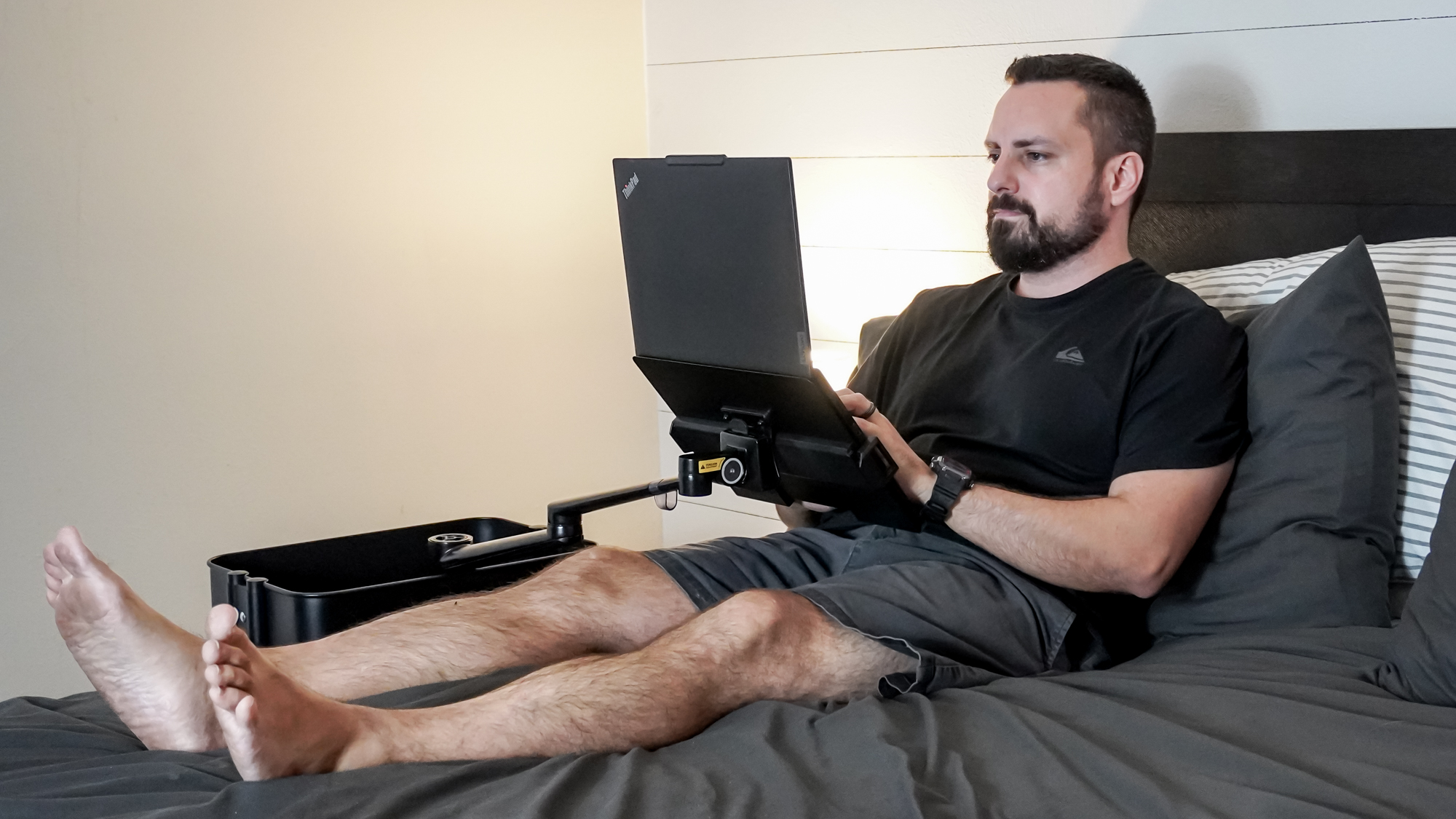 A person working on a laptop at a DIY rollable workstation from their bed