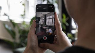 A person holds an iPhone with the Teleport by Varjo app recording a scene