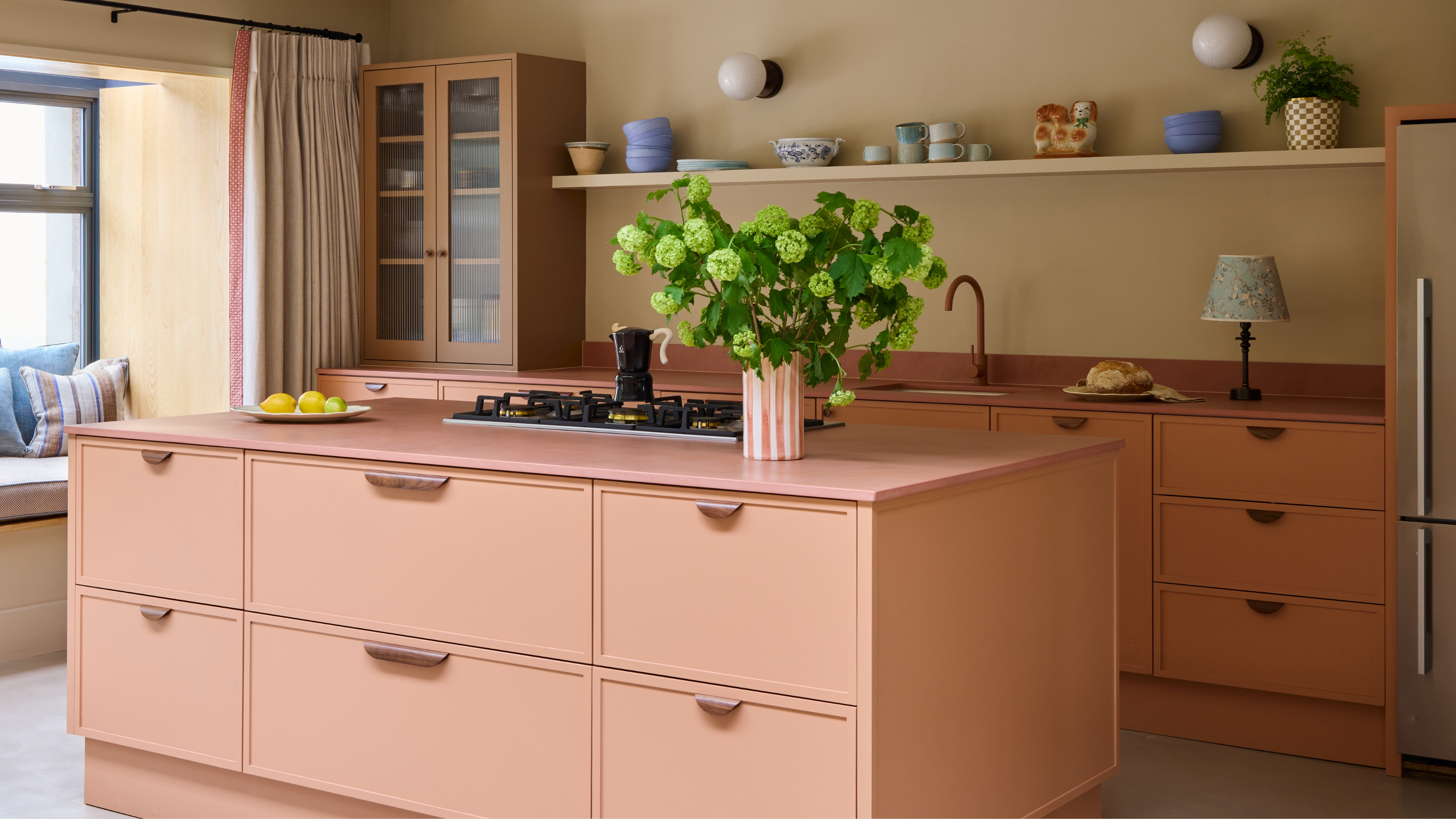 A contemporary kitchen in a soft contrast palette of pink, terracotta, wood, and stone colors and materials