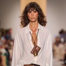 A Michael Kors model wearing a wallet necklace and a white button-down