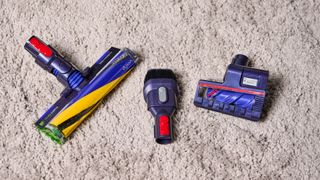 the dyson gen5detect cordless stick vacuum in prussian blue and copper, showing its cleaning head and attachment tools