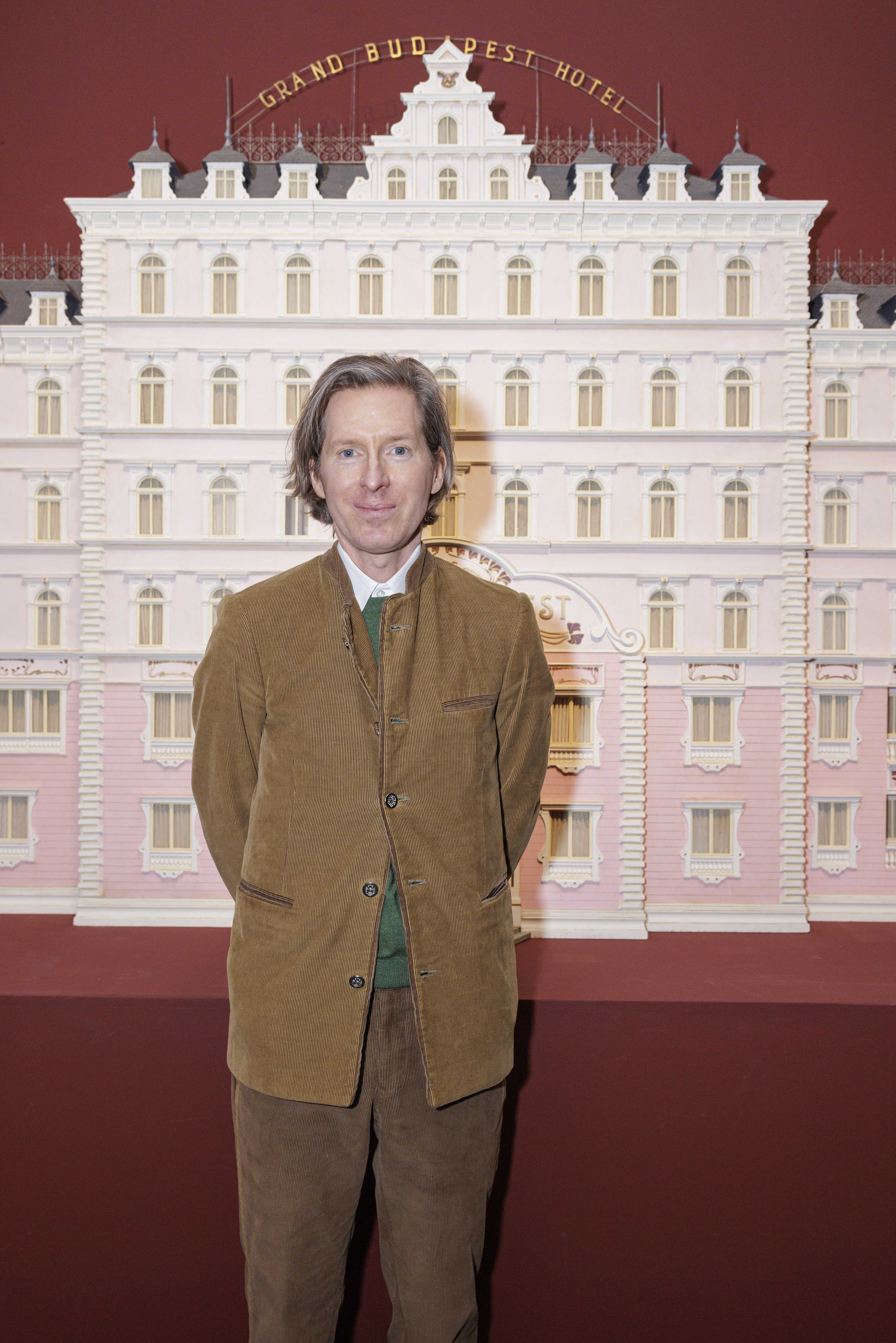 Wes Anderson in front of a model hotel at a past event
