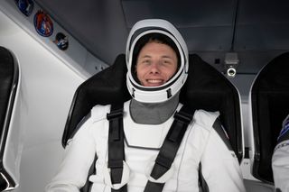 NASA astronaut Warren "Woody" Hoburg sitting in spacecraft seat with seatbelt on