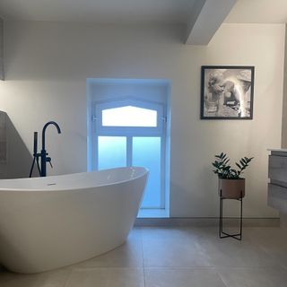 bathroom with freestanding bath and black floor standing tap