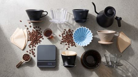 Collection of drip coffee makers on table with beans and filters