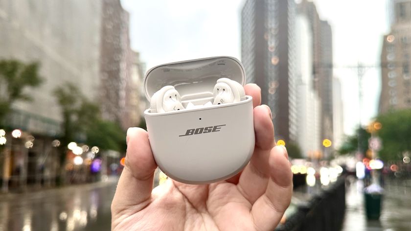 Someone holding the Bose QuietComfort Ultra Earbuds while outside