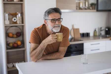 Man savoring the aroma of his morning coffee in a bright, contemporary kitchen