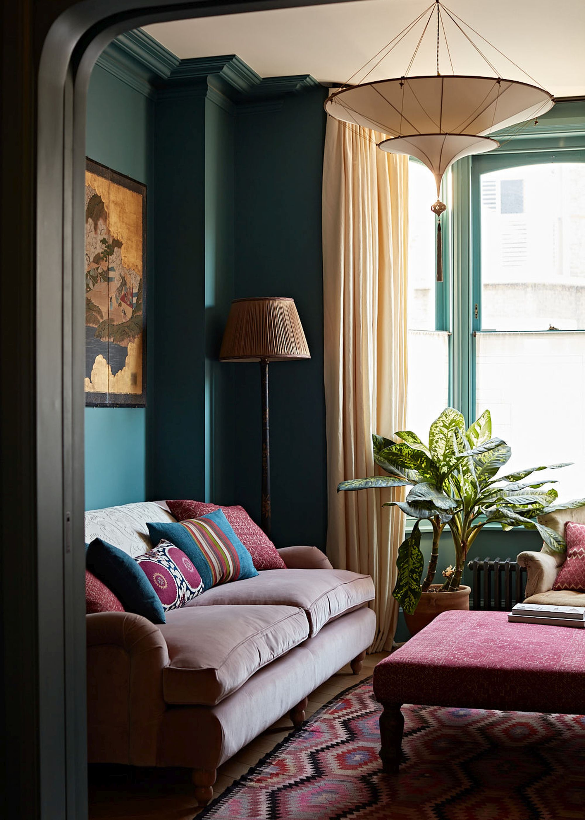 moody living room with dark green walls with bay window with cafe curtains and cream curtains