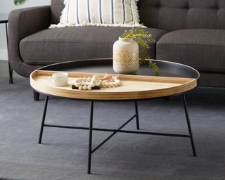 A two-tone round coffee table in light wood and black