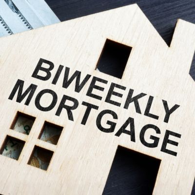 A wooden cut out shaped like a house with the word BIWEEKLY MORTGAGE on the front