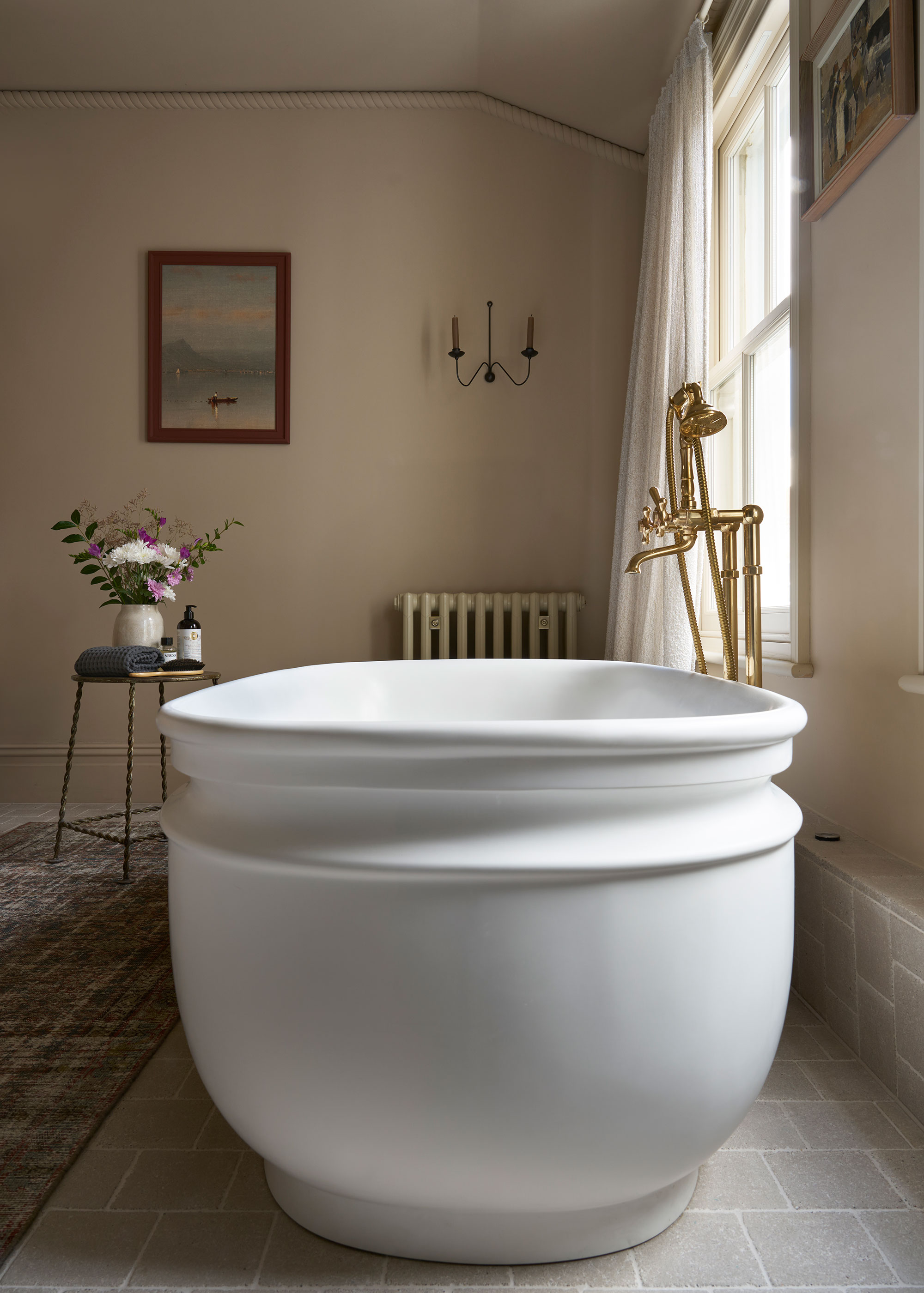 chunky freestanding bath in neutral bathroom with stone floor tiles
