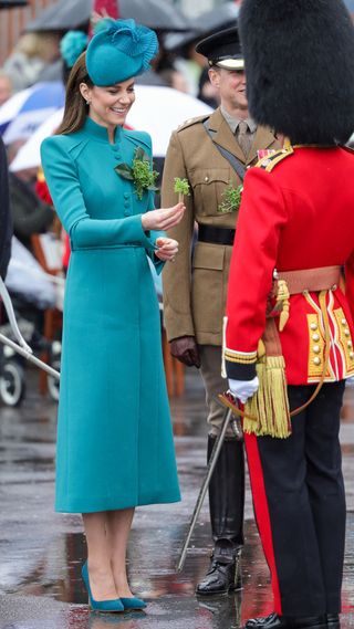 Catherine, Princess of Wales presents a traditional sprig of shamrock to an Officer during the St. Patrick's Day Parade