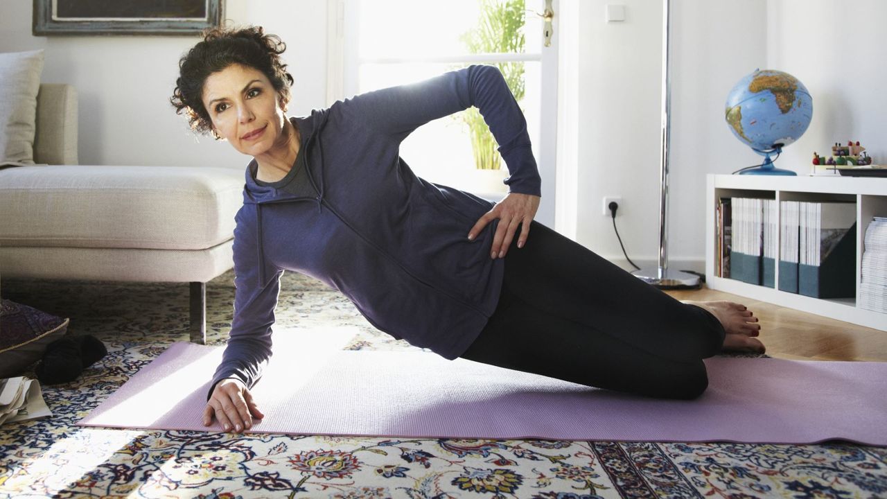 Woman doing a side plank exercise on her knees in living room