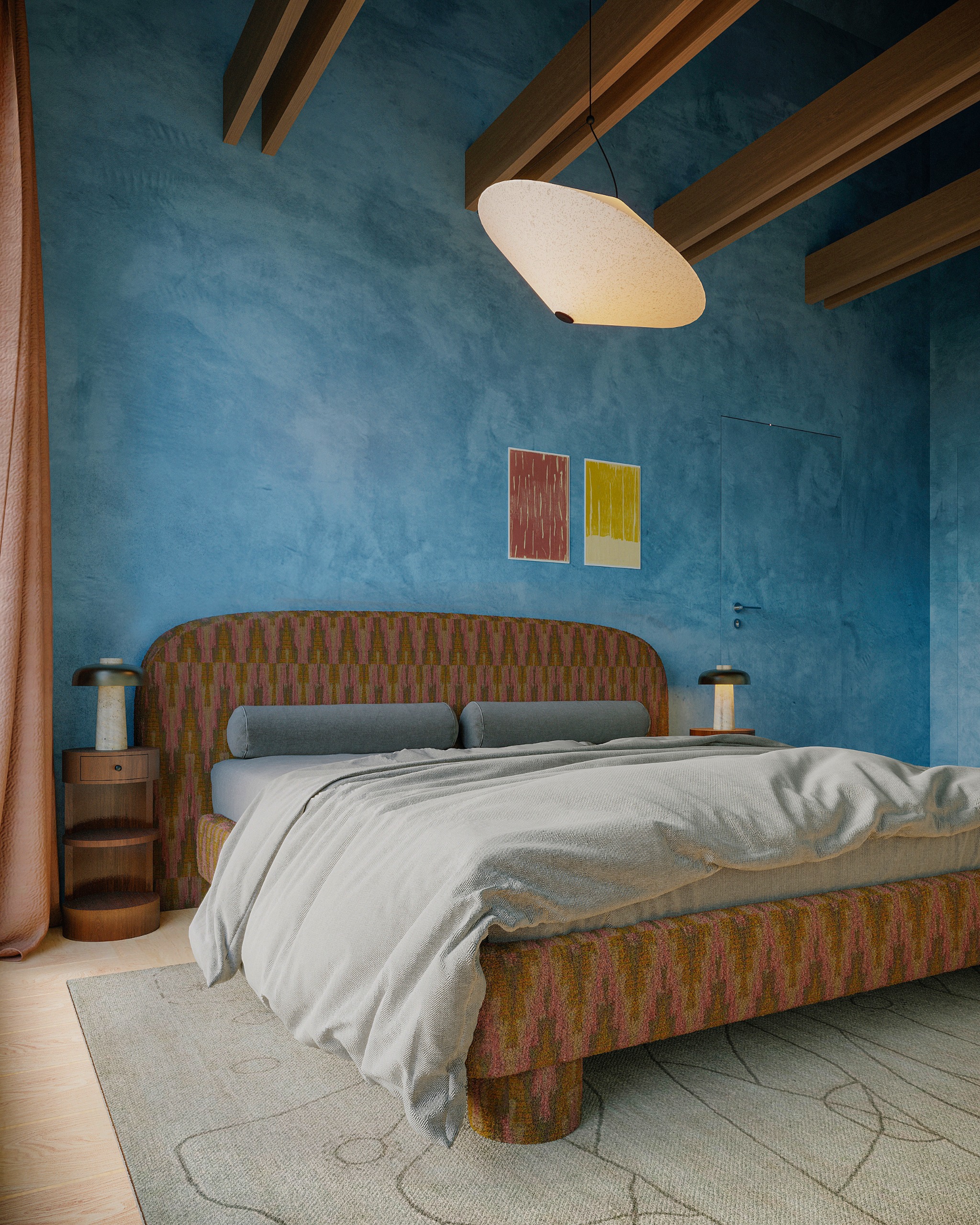 Bedroom with blue plaster walls, upholstered brown and pink patterned bed, grey covers and wood round side table