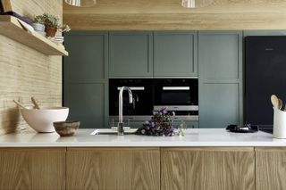 Wooden kitchen cabinets with white worktop and pale green cupboards