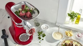 Red KitchenAid with a meat grinder attachment in a kitchen
