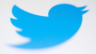 A close-up of a blue cartoon bird, the logo of Twitter, against a white background 