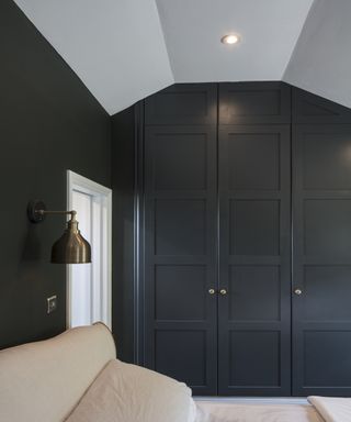 Black wardrobe and bed in mansard loft conversion bedroom