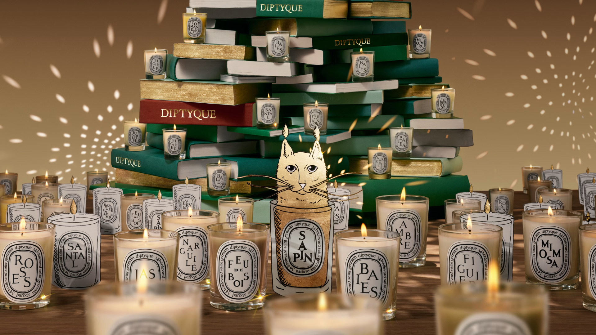 Diptyque holiday collection 2025 imagery with stacked books, lit candles, and illustrated cat image