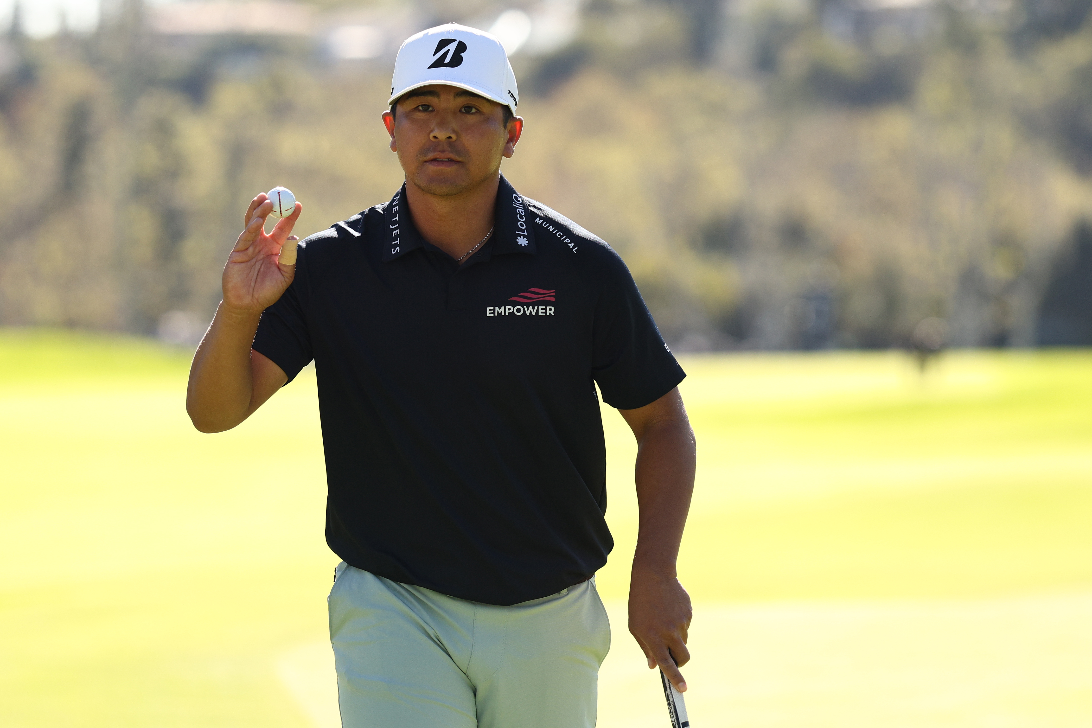 Kurt Kitayama waves to the crowd after holing a putt