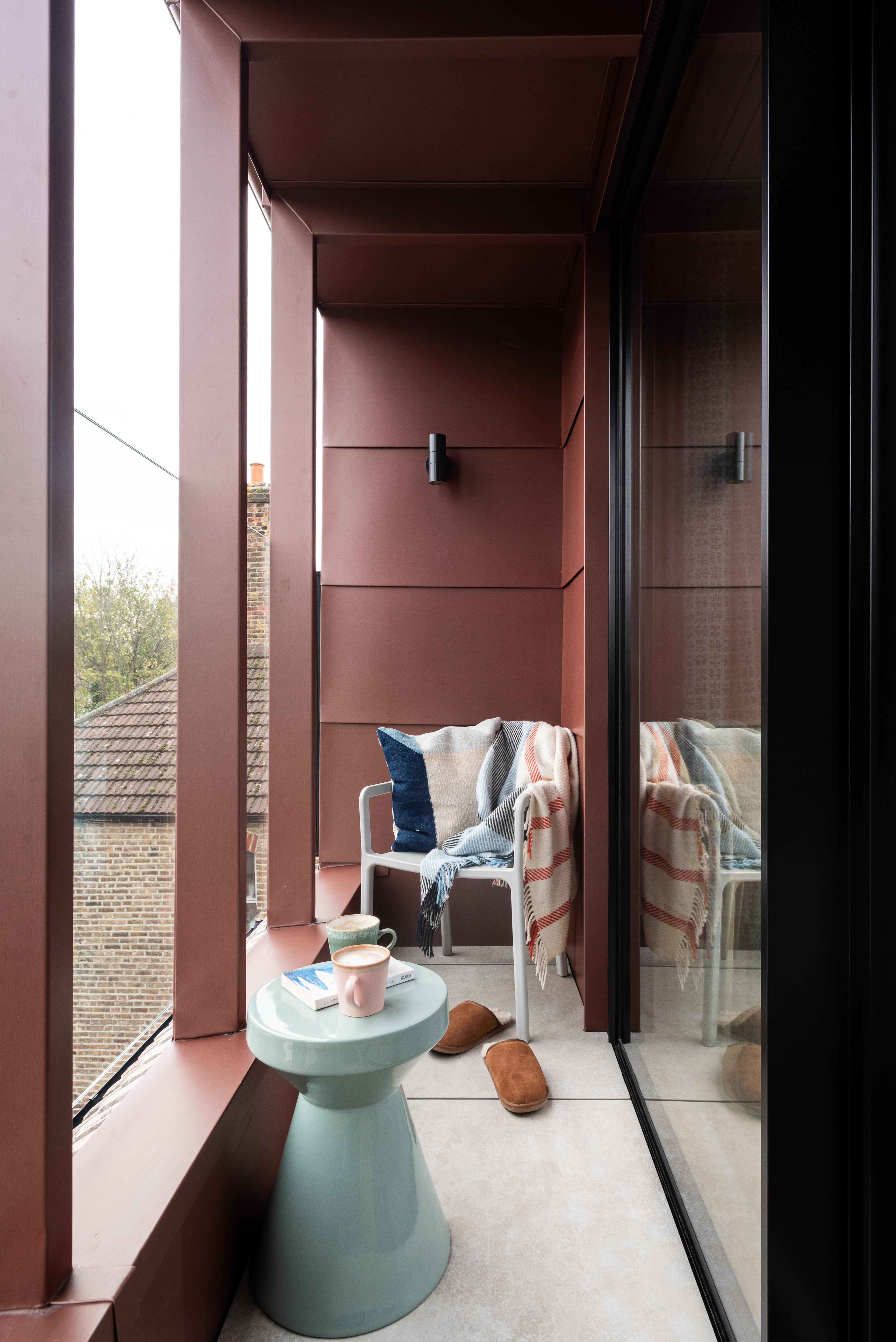 red steel balcony with a small blue coffee table and an outdoor chair
