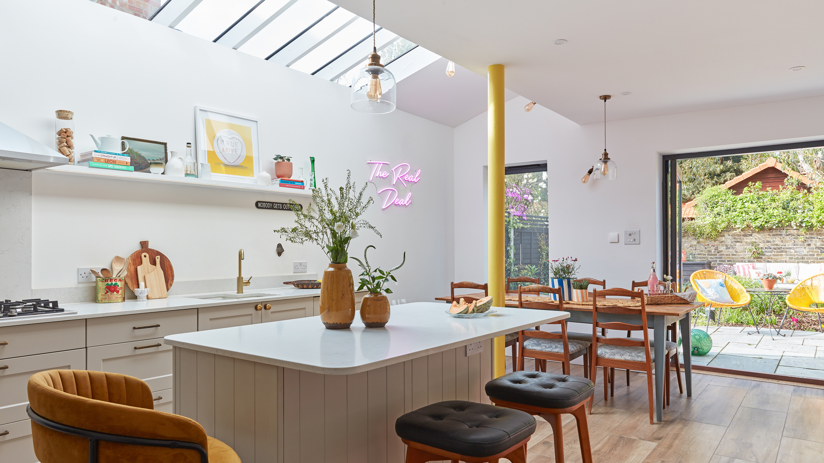 White kitchen with glazed roof over side return extension and a yellow pillow next to the kitchen island