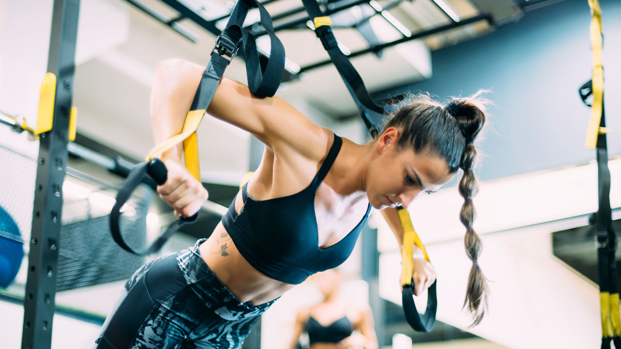 A woman exercising with TRX suspension trainers in the gym