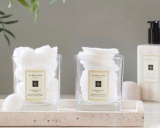 Two Jo Malone candle jars filled with cotton balls and cotton pads