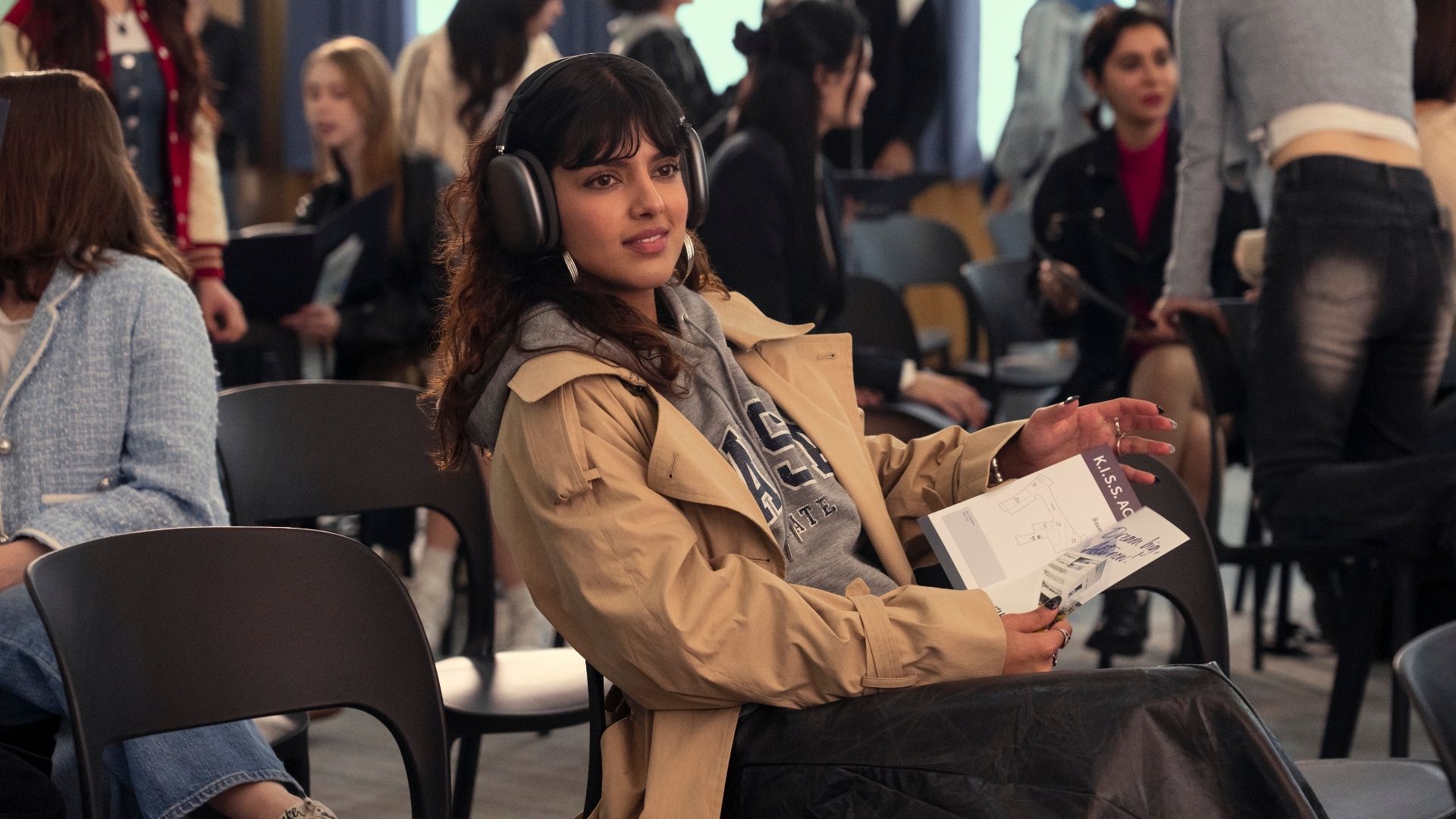 Praveena sits in a chair with a book in XO, Kitty