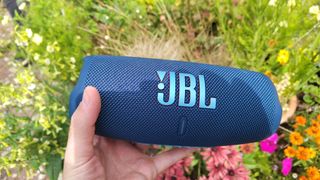 JBL Charge 5 being held in front of flowers