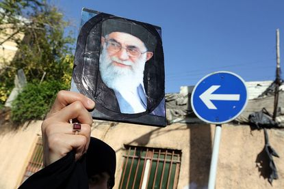 A person holds a picture of Ayatollah Ali Khamenei.
