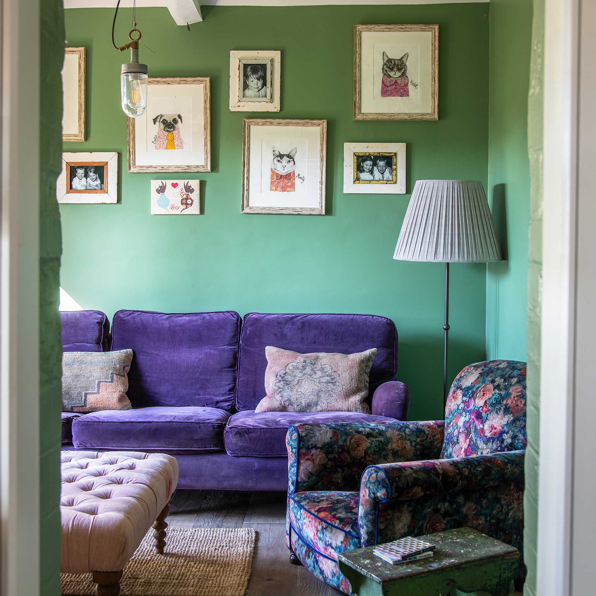 snug with bright green walls, purple velvet sofa, floral velvet armchair, vintage table and modern artworks
